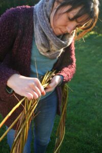 Christina weaving a large willow wreath outdoors in the winter